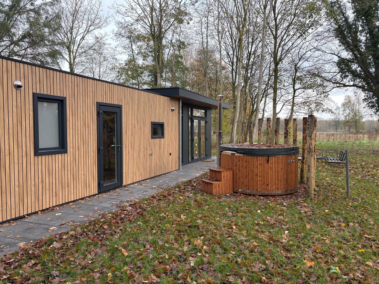 Lodge Drentsche Aa met houten gevel en houtgestookte hottub aan de bosrand